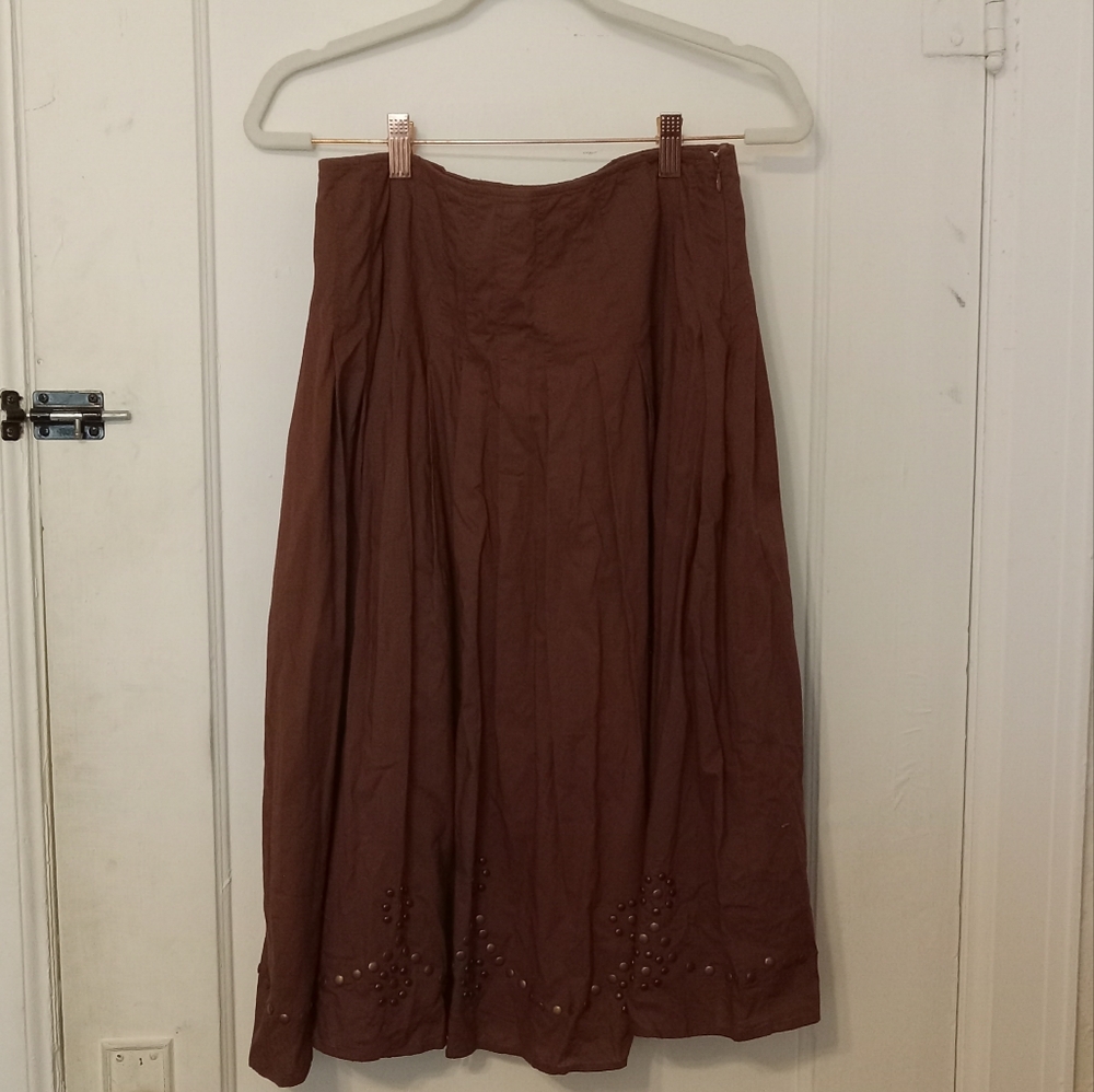 A brown, pleated skirt with metal accessories.